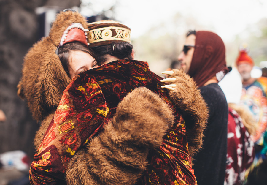a woman in a bear costume hugs a man in a velvet jacket